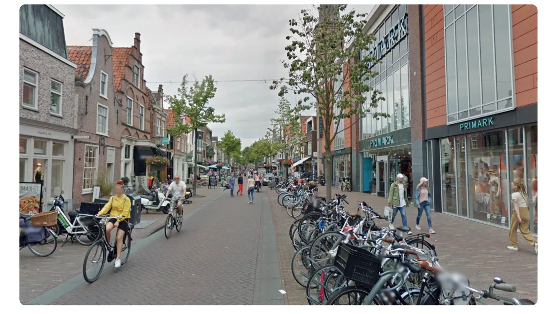 Foto van de winkelstraat Laat voor de herinrichting: een smalle straat vol geparkeerde fietsen, met winkelpuien aan weerszijden.