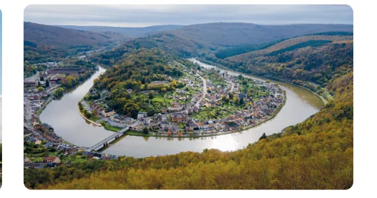 Luchtfoto van een sterk gebogen rivier met een stad in de bocht, omringd door heuvels.