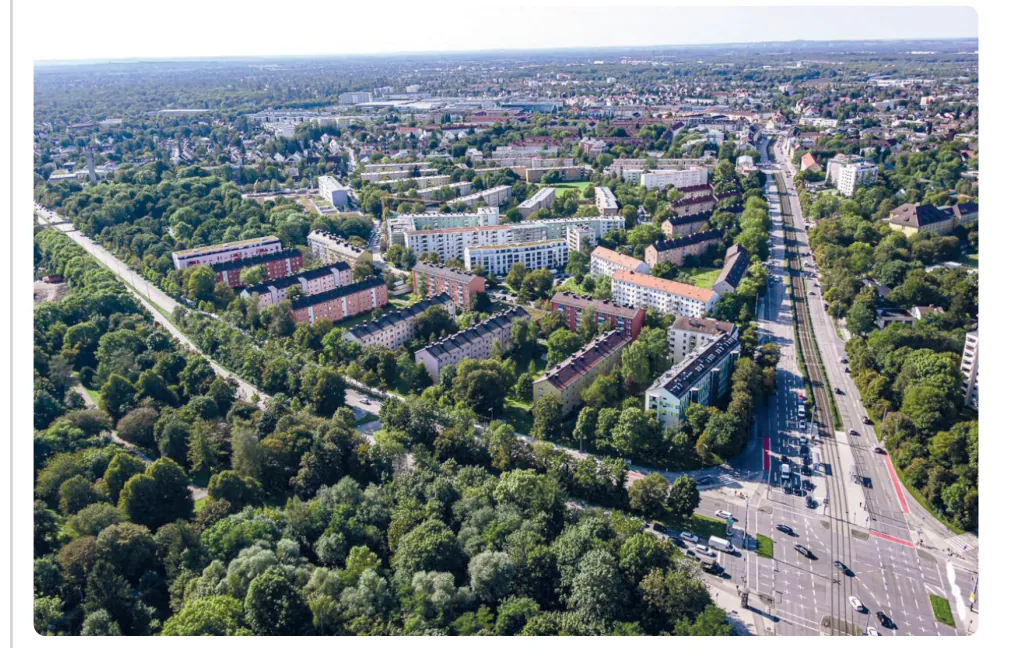 Luchtfoto van het stadsdeel Moosach met vooroorlogse en naoorlogse blokken woningen, groene bomenrijen en een drukke weg.