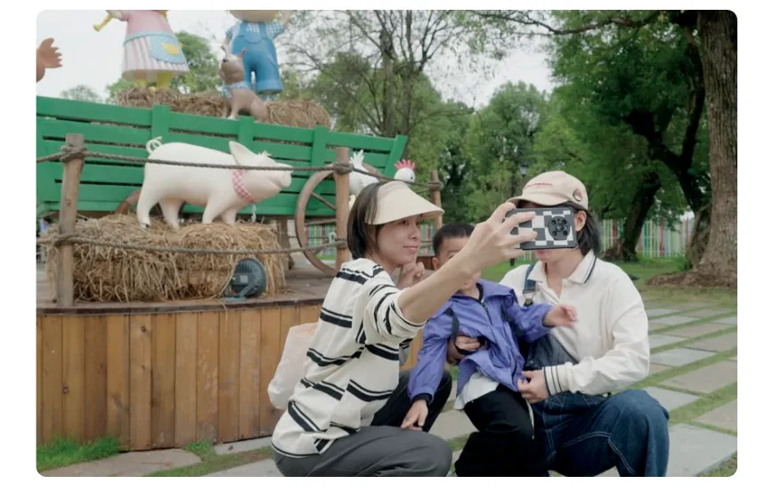 Foto van een gezin dat een selfie maakt in een themapark met een boerderijthema, met een beeld van een varken en een houten wagen.