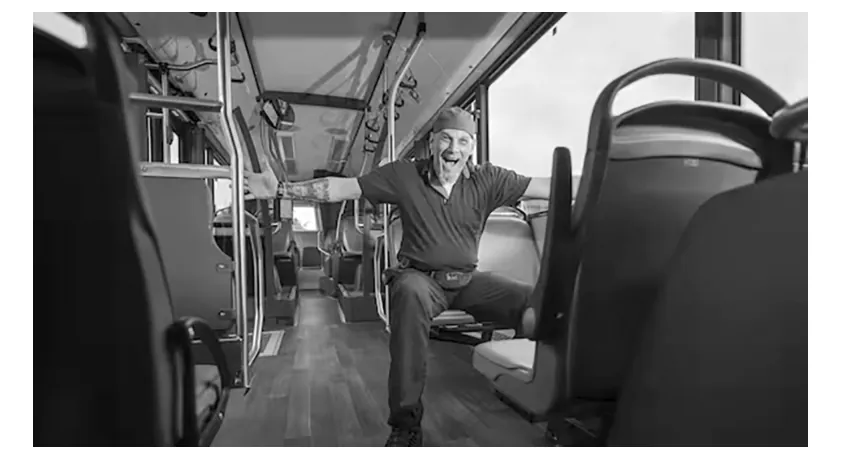Foto van een lachende man in een lege bus.