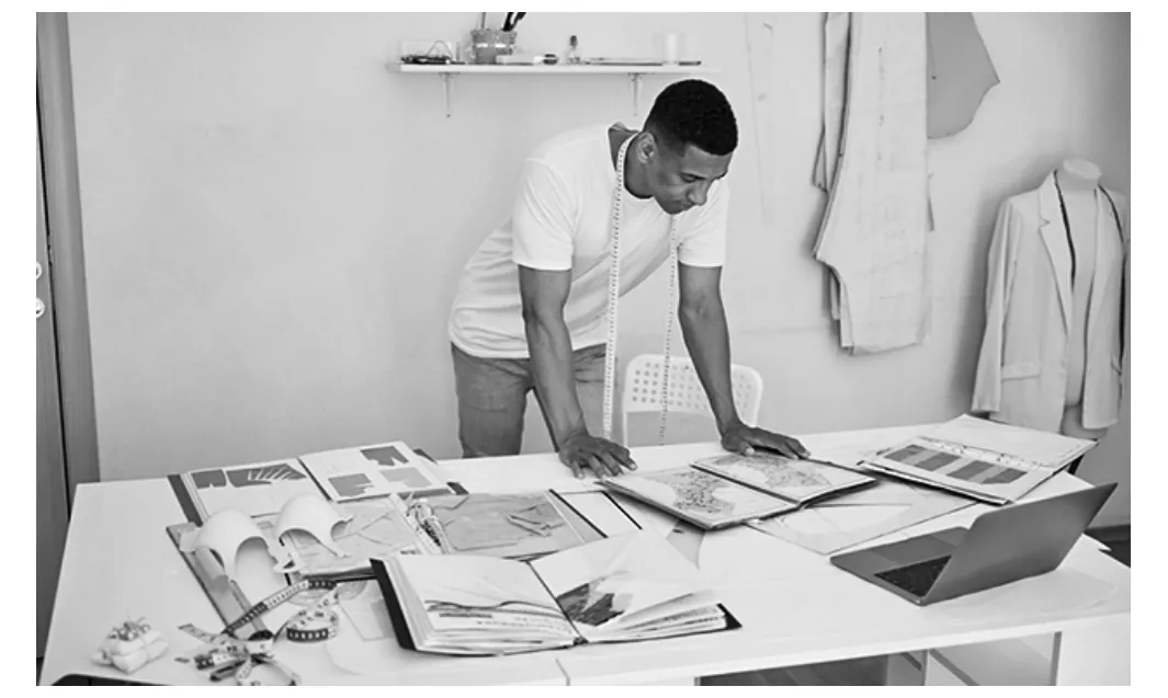 Foto van een man in een atelier die over ontwerpen op een tafel gebogen staat.