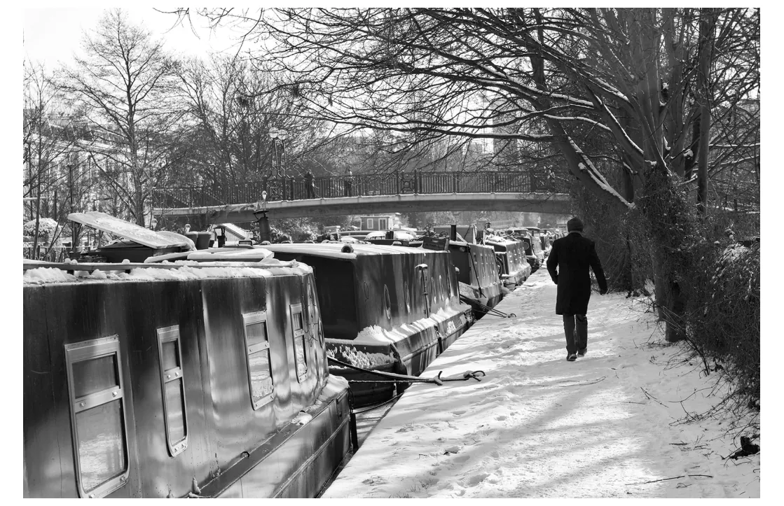 Foto van woonboten langs een besneeuwd kanaal.