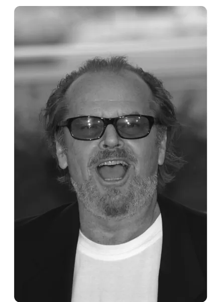 Zwart-wit portret van Jack Nicholson met zonnebril en een open mond.