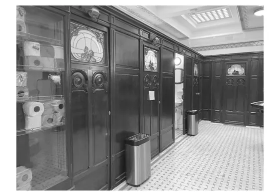 Foto van een historische openbare toiletruimte met houten deuren.