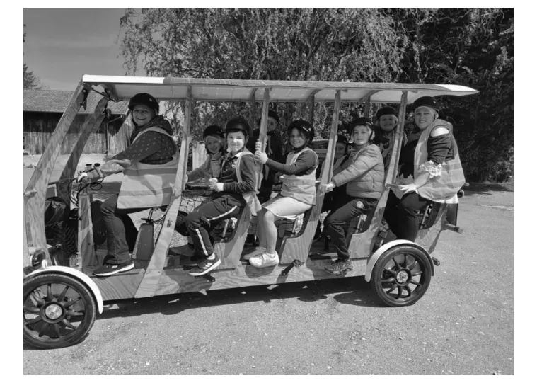 Foto van kinderen in een elektrisch schoolbusje met trapondersteuning.