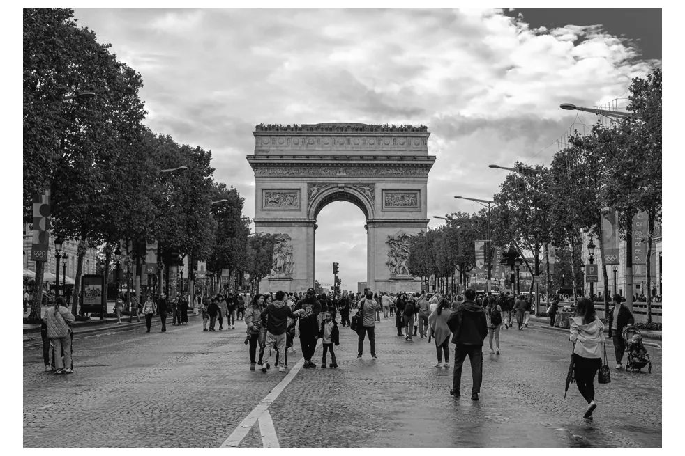 Foto van de Champs-Élysées met de Arc de Triomphe en veel wandelaars.