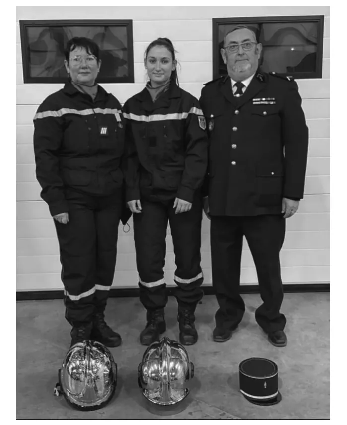 Foto van drie brandweermensen in uniform met hun helmen.