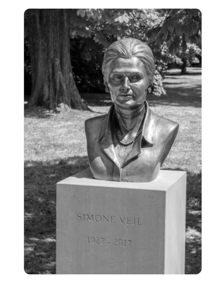Foto van een bronzen buste van Simone Veil op een stenen sokkel met haar naam en levensjaren, in een park.