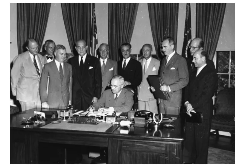 Foto van de Amerikaanse president die een verdrag tekent, omringd door mannen in pak.