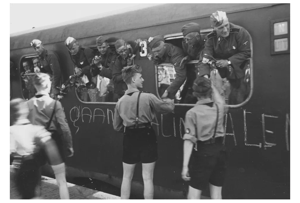 Foto van Nederlandse soldaten in Duitse dienst uit een treinraam, met op de trein de tekst Wij gaan Stalin halen.