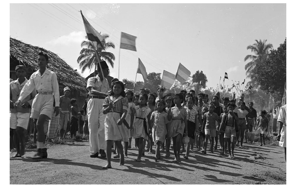 Foto van Indonesische kinderen in een optocht met Nederlandse vlaggen.