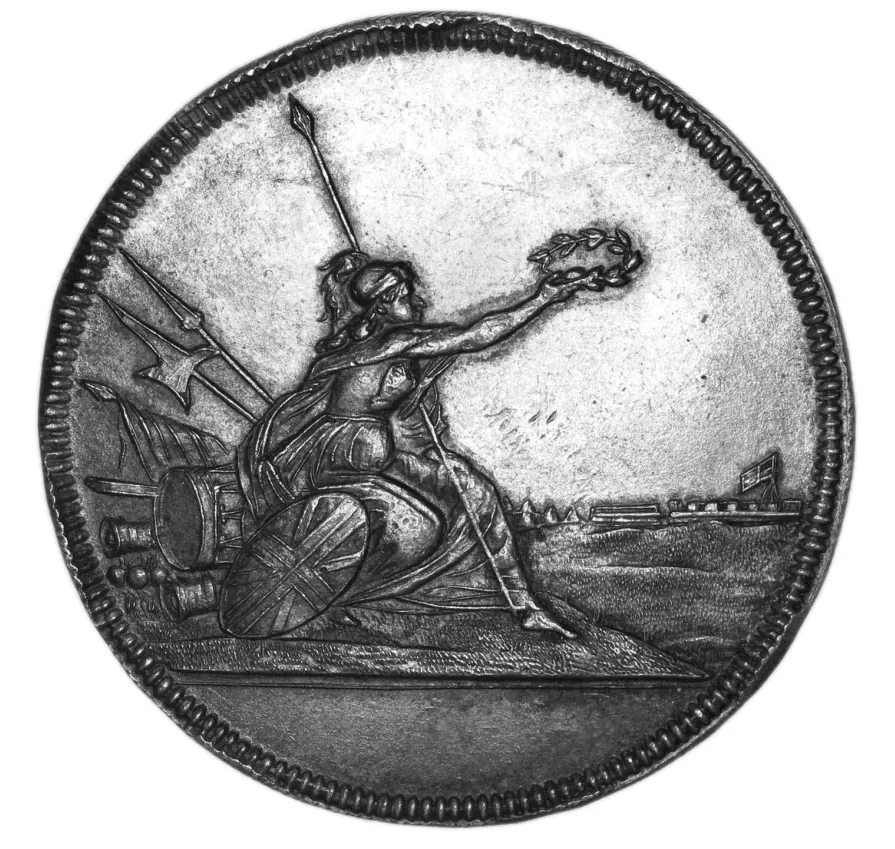 Metalen medaille met een vrouwelijke figuur, Brittannia, die een lauwerkrans vasthoudt. Op de achtergrond een fort met een vlag.