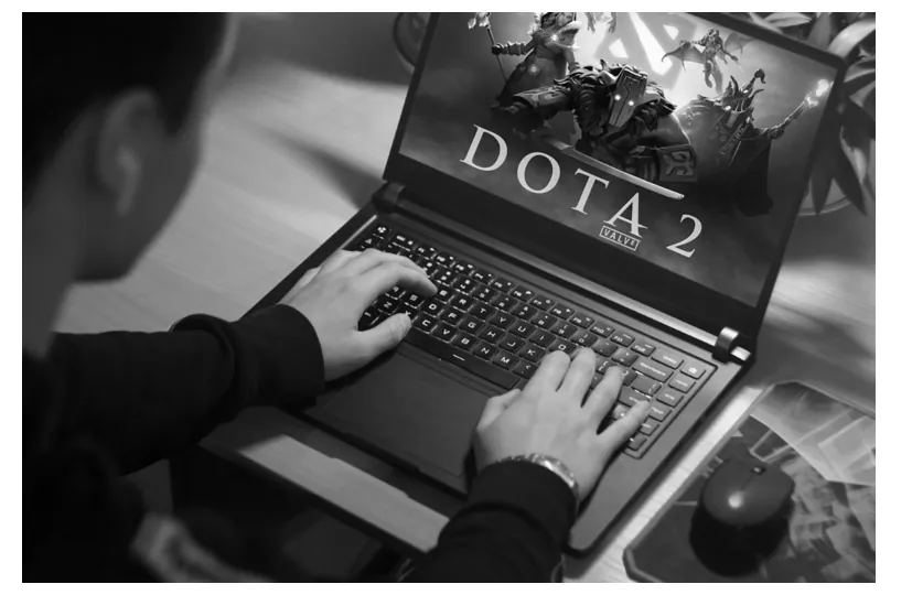 Foto van twee handen die op een laptop met het Dota 2-logo typen.