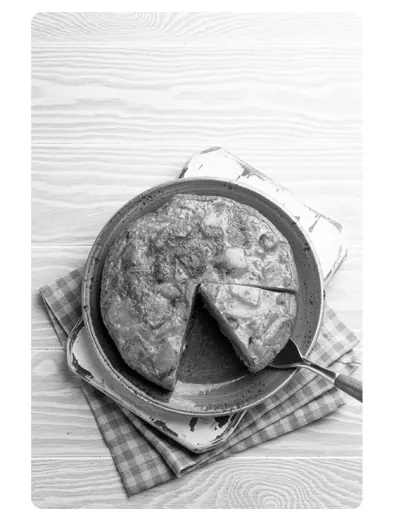 Zwart-witfoto van een ronde schotel met tortilla, waarvan een punt is afgesneden, op een geruit servet.