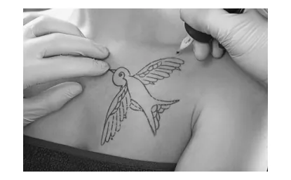 Foto van een tatoeëerder die een vogeltatoeage zet op de borst van een persoon; de vogel heeft uitgespreide vleugels.
