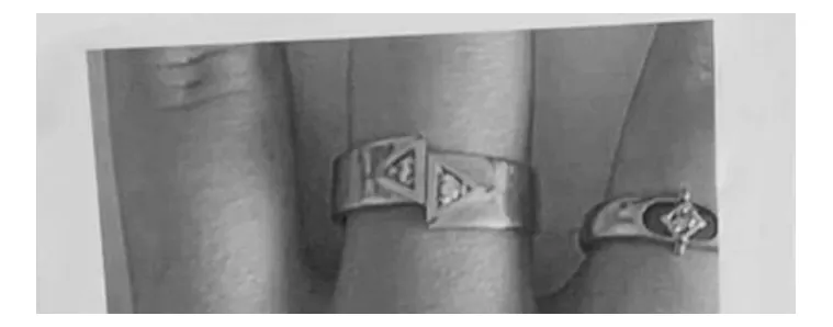 Foto van een vinger met twee zilverkleurige ringen; de ring in het midden heeft een geometrisch motief.