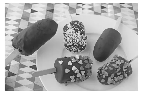 Foto van vier met chocolade overgoten bananenijsjes op stokjes, op een bord met een geometrisch patroon.
