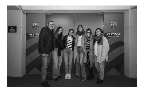 Zwart-witfoto van een groep van zes bezoekers die poseren voor de deur van een kleedkamer in het stadion van FC Barcelona.