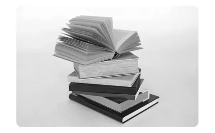 Een stapel boeken, het bovenste boek opengeslagen.