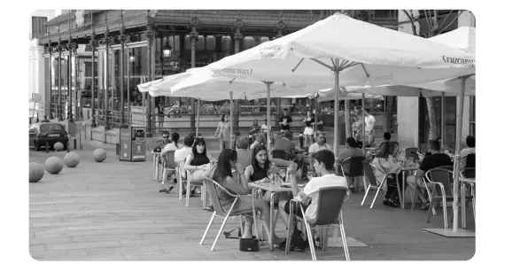 Zwart-witfoto van een terras met parasols waar mensen aan tafeltjes zitten.