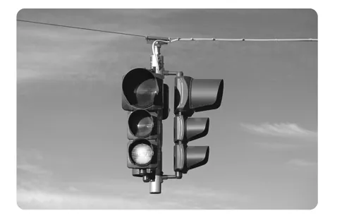 Zwart-witfoto van een verkeerslicht dat aan een kabel boven de straat hangt.