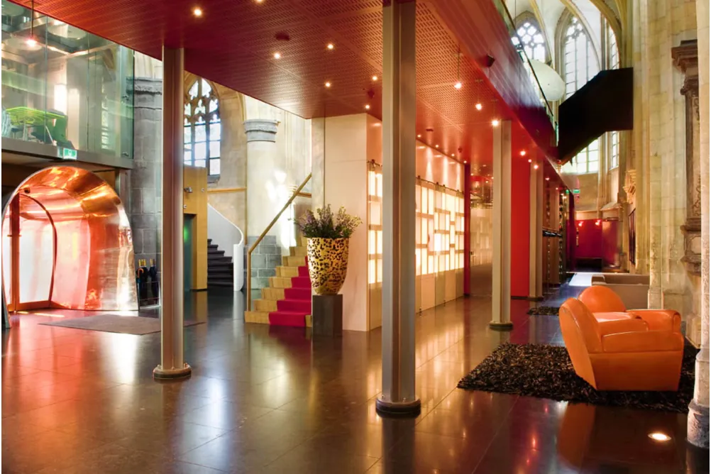 De centrale hal in het schip van de kerk, waar links de koperen tunnel uitkomt; rood plafond, een trap met rode loper, zuilen en een glanzende vloer.