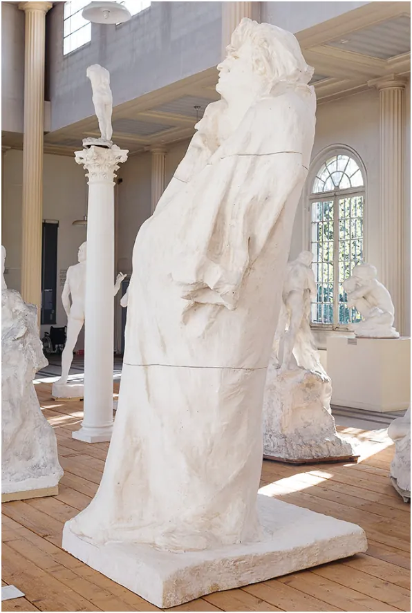 Wit gipsen beeld van Balzac in een museumzaal: een staande figuur, helemaal gehuld in een lange mantel zonder zichtbare armen, met het hoofd achterover geheven, op een lage plint.