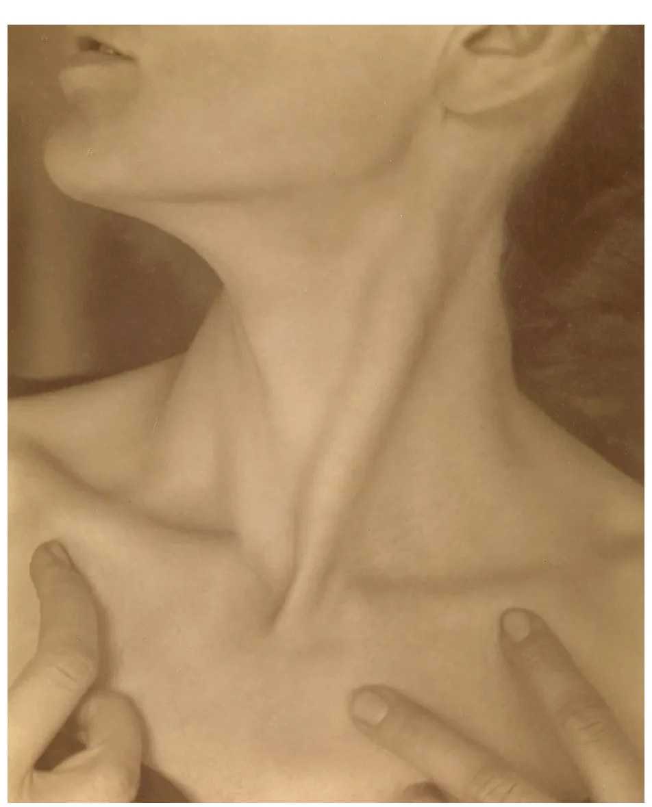 Sepia foto van een schouder en een hand, van dichtbij, met zachte schaduwen.