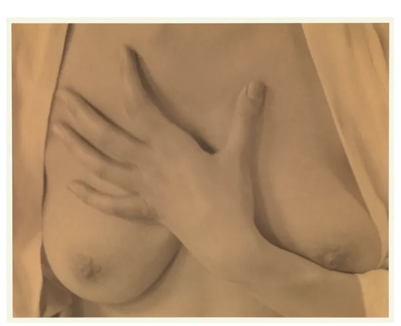 Sepia foto van een hand die over een lichaamsdeel ligt, van dichtbij en in zachte belichting.