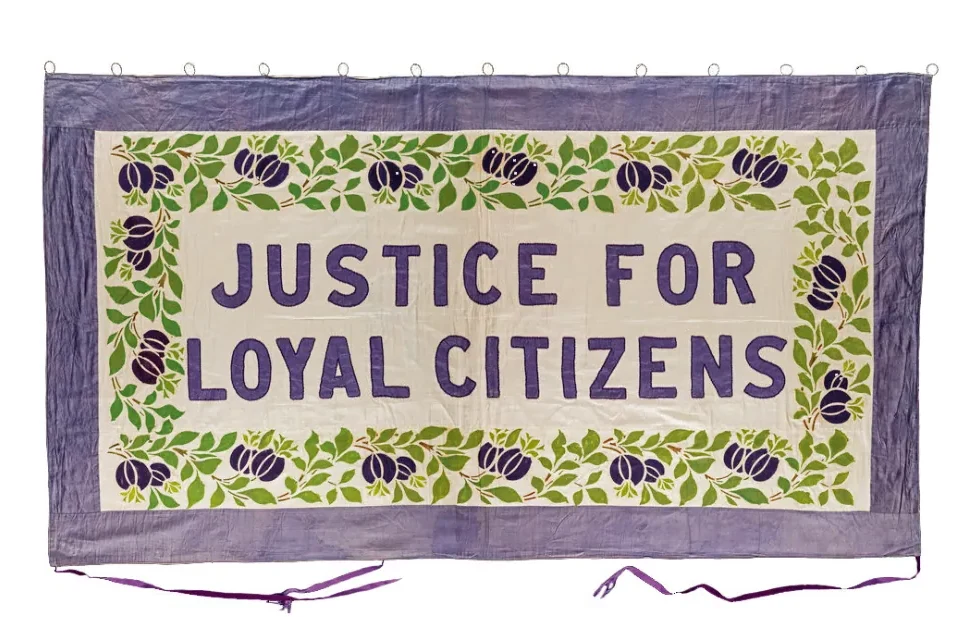 Lila vaandel met een groene bladerrand met paarse bessen; in het midden staat in grote paarse letters JUSTICE FOR LOYAL CITIZENS.
