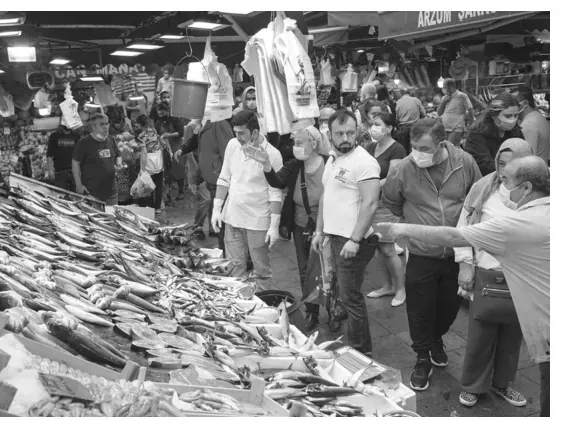 Foto van een drukke markt met vis en kopers.