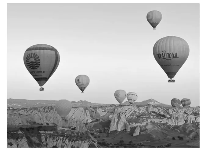 Foto van heteluchtballonnen die boven een landschap van rotsformaties zweven.