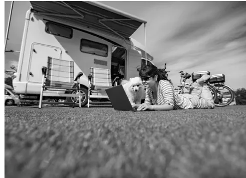 Zwart-witfoto van een camper met uitgeklapt zonnescherm op het gras.