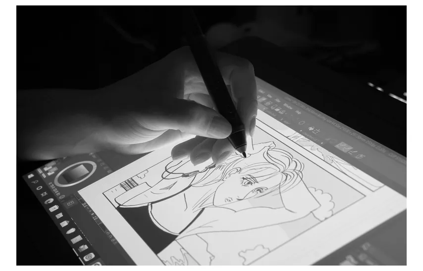Zwart-witfoto van een hand die met een pen op een tekentablet een animatiefiguur tekent.