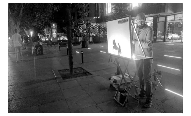 Foto van een man die op straat achter een verlicht scherm een schimmenspel speelt.
